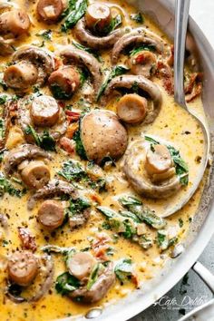 a pan filled with mushrooms and spinach on top of a table next to a fork