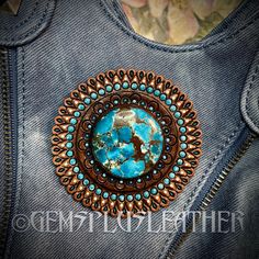 a denim jacket with a blue and brown broochle on the back of it