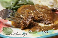 a plate with mashed potatoes, green beans and gravy on it next to a fork