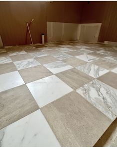 the floor is covered with white and brown marble tiles, which are being worked on