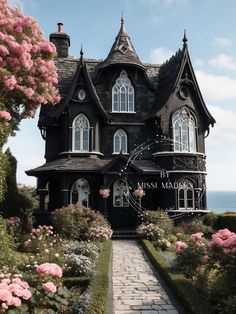 a black and white victorian style house with pink flowers in front of the entrance to it