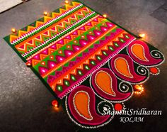 an intricately decorated rangolite design on the ground with candles in front of it