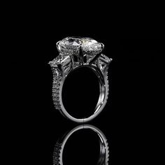 a diamond ring on a black background with reflection in the middle and side stones around it