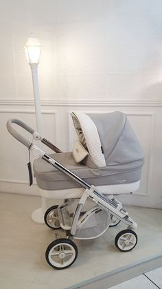 a baby stroller sitting on the floor next to a light pole with a lamp in it