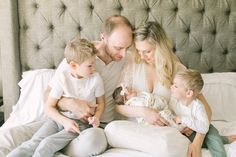 a man, woman and two children are sitting on a bed with the baby in his arms