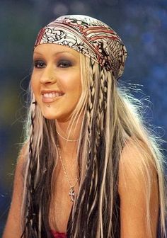 a woman with long hair wearing a bandana and braids on her head is smiling