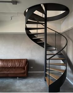 a living room with a leather couch and a spiral staircase in the middle of it