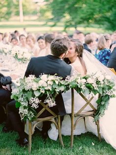 the bride and groom are kissing at their wedding ceremony in front of an outdoor audience