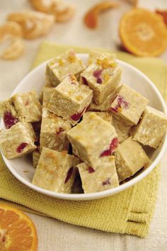 a white bowl filled with oranges and cranberry squares