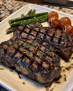 a plate with steak, asparagus and tomatoes on top of it next to some green beans