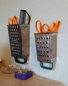 two metal holders with orange scissors on them