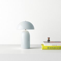 a table lamp sitting on top of a white shelf next to a stack of books