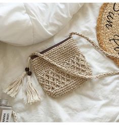 a crocheted purse sitting on top of a bed next to an empty bottle