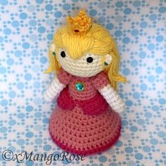 a crocheted doll is wearing a pink dress with a gold crown on her head