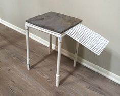 a small white table sitting on top of a hard wood floor next to a wall