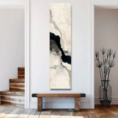 an abstract painting hangs on the wall next to a wooden bench in a white room