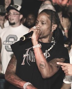 a man with dreadlocks is singing into a microphone in front of a crowd