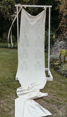 a white wedding dress hanging on a clothes rack in the grass with an information sheet attached to it