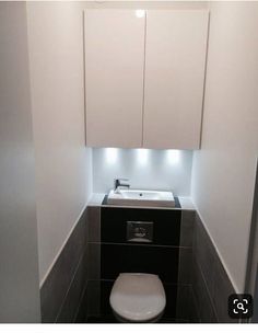 a white toilet sitting in a bathroom next to a wall mounted cabinet with lights on it