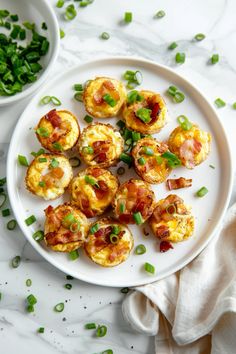 small appetizers with bacon and green onions on a white plate next to a bowl of peas