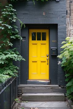 a yellow door is on the side of a black building with plants growing around it