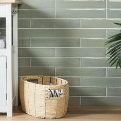 a basket sitting on the floor next to a shelf with towels and a towel dispenser