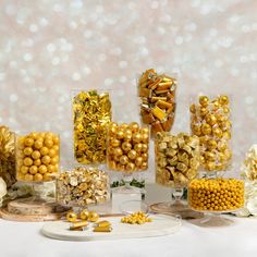 a table topped with lots of different types of candies and candy bar containers filled with gold colored candies