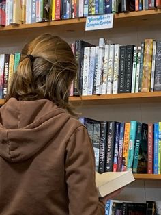 a woman standing in front of a book shelf filled with books