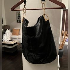 Black Leather W/Gold Accessories Chic Evening Hobo Bag With Branded Hardware, Chic Hobo Bag With Branded Hardware For Evening, Chic Hobo Tote Bag With Branded Hardware, Elegant Hobo Bag With Chain Strap For Shopping, Elegant Black Hobo Bag With Chain Strap, Black Bucket Hobo Bag With Gold-tone Hardware, Black Saffiano Leather Bag With Gold-tone Hardware, Black Leather Shoulder Bag With Gold-tone Hardware, Black Shoulder Bag With Gold-tone Hardware