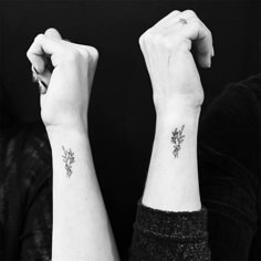 two women with matching tattoos on their arms, one holding the other's hand