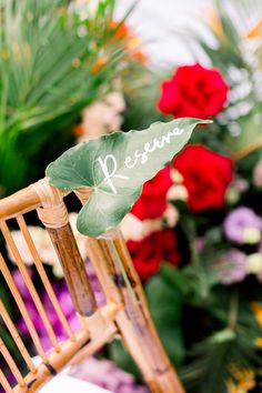 a wooden chair with a green leaf on top of it next to red and purple flowers