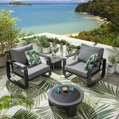 two chairs and a table sitting on top of a patio next to an ocean view