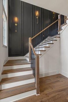 an empty room with black walls and wooden floors, two lights are on the wall next to the stairs