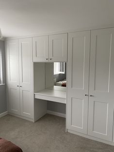 an empty bedroom with white cabinets and drawers