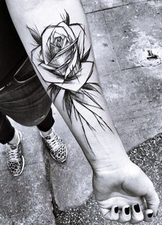 a black and white photo of a rose tattoo on the arm, with leaves around it