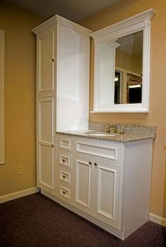 an empty bathroom with white cabinets and marble counter tops, along with a mirror on the wall