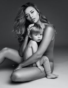 a woman sitting on the floor with a child in her lap and holding it up to her chest