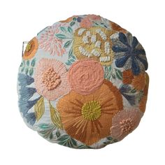 an embroidered round pillow with flowers on it