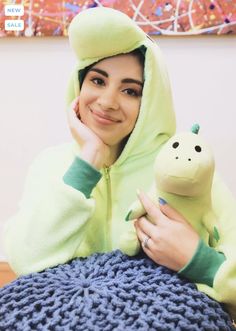 a woman in a green hoodie holding a stuffed animal on top of a blue blanket