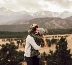 a man and woman embracing each other in the mountains