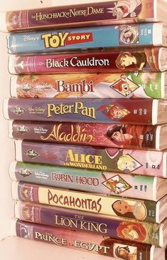 a stack of disney movies sitting on top of a white shelf