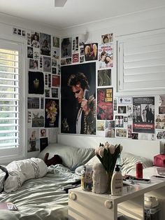 a bed room with a neatly made bed and lots of pictures on the wall above it