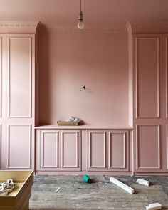 a room with pink walls and wooden paneling on the floor, including a bench