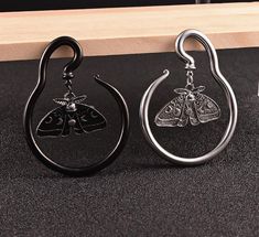 two black and silver earrings with moths on them