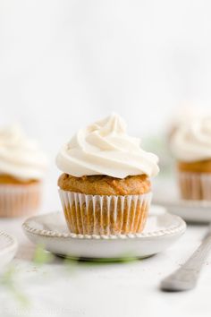 cupcakes with white frosting on small plates