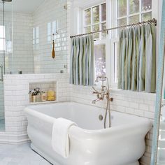 a white bath tub sitting under a bathroom window