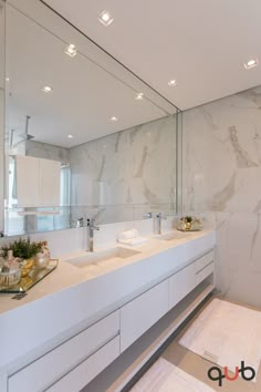 a large bathroom with two sinks and mirrors on the wall next to eachother