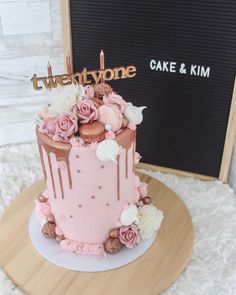 there is a pink cake with flowers on it and the name twentyone written in gold