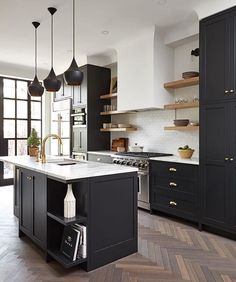 a large kitchen with black cabinets and white counter tops, an island in the middle