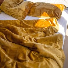 an unmade bed with brown sheets and pillows